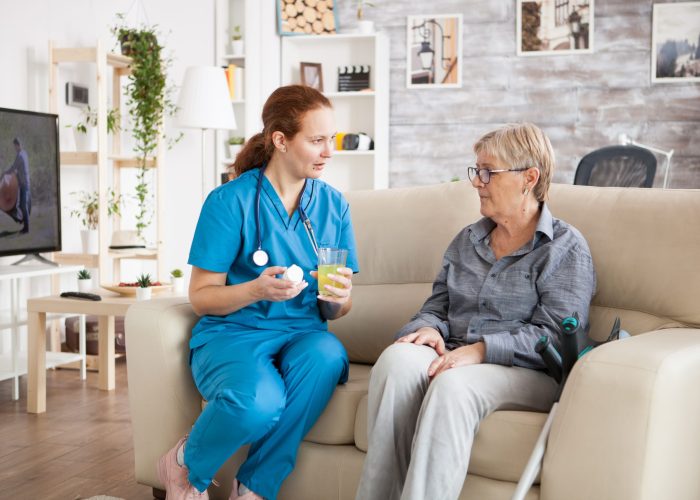 Female doctor talking with senior woman in nursing home about new drug pills
